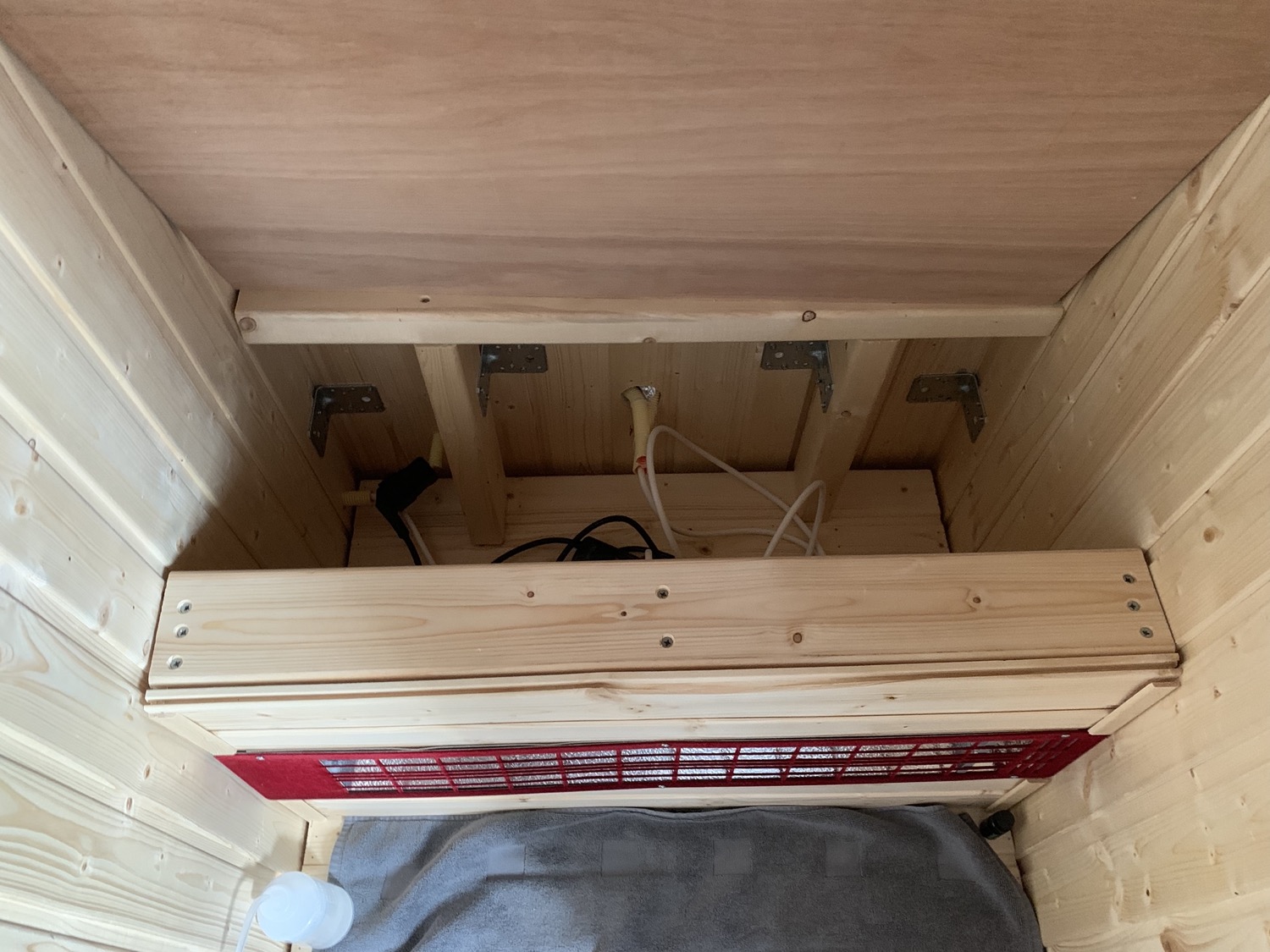 The top part of the bench lifts up. The space under the bench hides the electrical wiring: one plug per heater + an extension cord. Power comes in via a hole in the back wall.