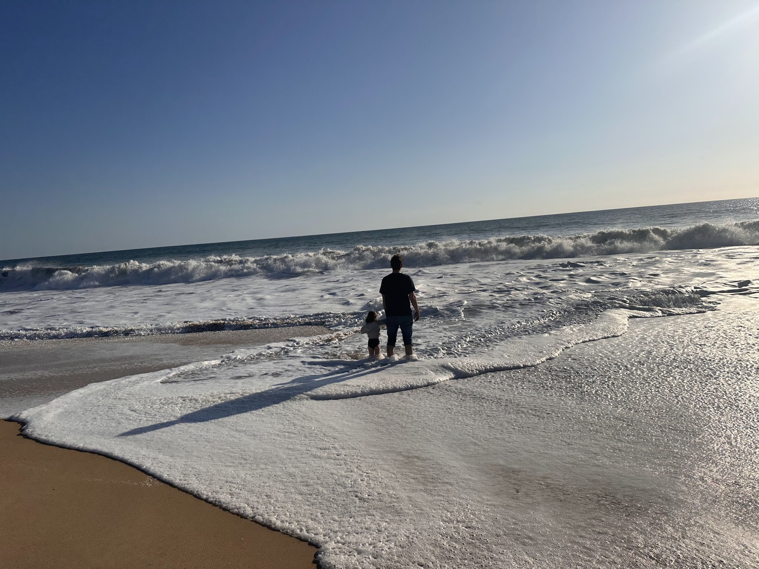 My daughter and I, standing in the shoreline waves watching the horizon, the evening before we left for home.